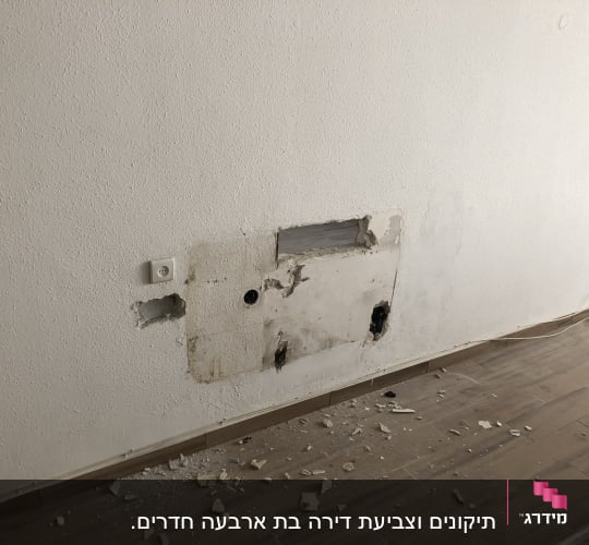 קיר עם חור ותיקונים, שברי טיח על הרצפה